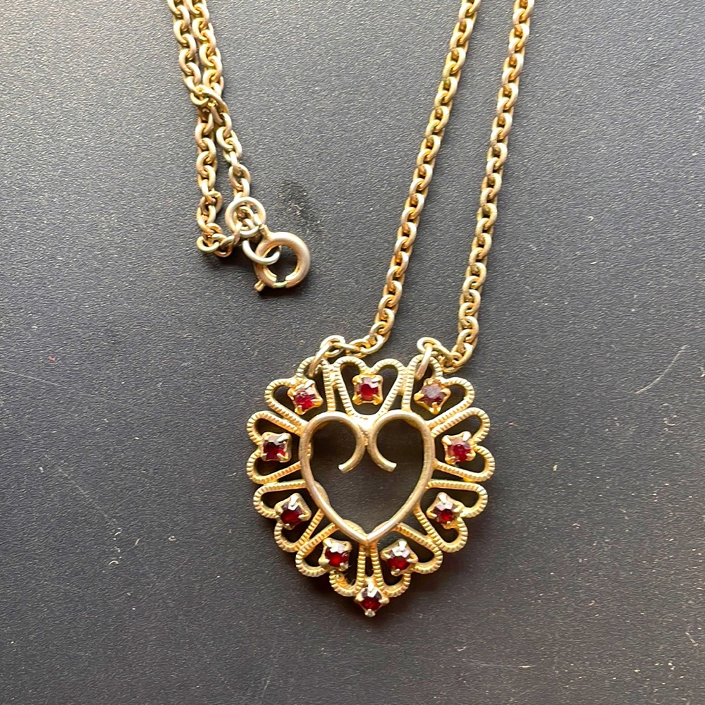 Golden heart necklace surrounded by red gemstones